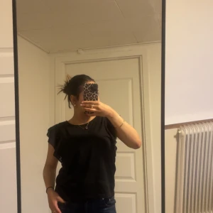 Svart blus med volangärmar - Svart blus med breda volangärmar och spetsdetaljer längs ärmsluten. Blusen har rund halsringning och en loose passform som ger en avslappnad vibe. Perfekt att styla med jeans eller kjol för en trendig look.