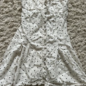 Vit prickig kortklänning från Zara!💕 - Supersöt vit kortklänning från Zara med svarta prickar, knappar framtill och snörning i ryggen. Klänningen har tunna axelband och är gjord i ett lätt bomullstyg, perfekt för varma dagar!. Sitter snyggt och har en feminin passform.💕 Men väldigt kort❤️⭐️