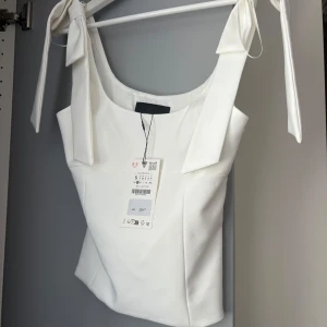 Vit linnetopp med knytband från Zara - Säljer en helt ny populär topp från Zara som inte säljs längre. Nypris är 329 kr men kan tänka mig sälja den för 300 eller byta till en likadan i storlek M🥰