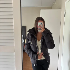 Stella McCartney adidas jacka  - Säljer en svart pufferjacka från Adidas Stella McCartney. Jackan har hög krage, dragkedjor, spänne på ärmen och coola detaljer. Materialet är syntet och polyester, perfekt för kalla dagar. Snygg och sportig look med markerad midja och flera fickor.