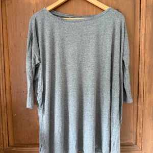 Grå loose trekvarts T-shirt - Enkel och oversized grå långärmad tröja i mjukt material. Tröjan har rund halsringning och avslappnad passform, perfekt för en chill och bekväm stil. Passar dig som gillar basic och minimalistiskt.