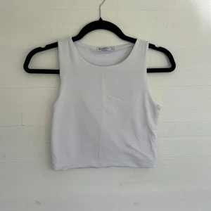 Vit croppad linnetopp från Stradivarius - Säljer en stilren vit croppad linnetopp från Stradivarius. Toppen är ärmlös med rund halsringning och har en enkel, clean look som passar perfekt till jeans eller kjol. Materialet är mjukt och stretchigt för en bekväm passform. Storlek L men skulle säga att den passar M och S också🤩💕