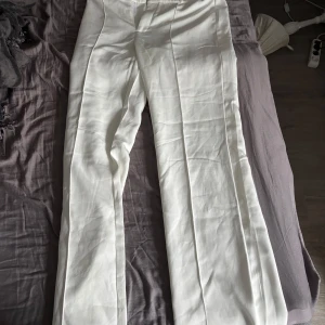 Vita kostymbyxor madlady- Tall - Snygga vita kostymbyxor med medel midja och utsvängda ben. Byxorna har pressveck framtill och en klassisk passform som ger en stilren look. Perfekta för varmare dagar och enkla att matcha med olika toppar. Endast använda en gång.