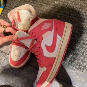 Nike Air Jordans i rosa och vitt - Säljer ett par klassiska Nike Air Jordans i rosa och vitt. Skorna har högt skaft, snörning och den ikoniska Air Jordan-loggan på sidan. Perfekta för dig som vill sticka ut med en sportig och tidlös look.