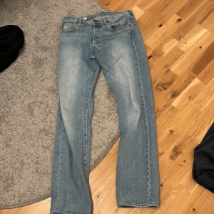 Levis 501 ljusblå jeans - Klassiska Levis 501 jeans i ljusblå tvätt med raka ben och normal passform. Jeansen är lite slitna längst ner på ena byxbenet. 
