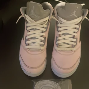 Nike Air Jordans 5 Retro i ljusrosa och grå (2022) - Säljer ett par Nike Air Jordans 5 Retro i ljusrosa med grå detaljer och vit sula. Skorna har klassisk snörning ( detta är inte orginal skosnörena men man får såklart med dem också, fråga bara så skickar jag bild på de också), meshpaneler på sidorna och en genomskinlig yttersula. Perfekta för dig som vill sticka ut med stilrena sneakers. Jag har inte lådan då jag köpte dessa när jag var i usa men hade inte plats att ta med lådan hem! Priset är inte hugget i sten!
