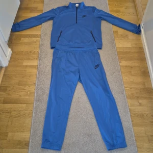 Blå träningsbyxor från Nike. Storlek L har änvänd den 3 gånge barar - Säljer ett par blå träningsbyxor från Nike med resår i midjan och vid bensluten. Byxorna har en sportig look och är tillverkade i ett lätt syntetmaterial som passar perfekt för träning.