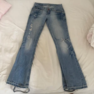 Lowwaist bootcut jeans - Såå snygga jeans!!! Med hål, ljusblå. Bra skick! Men jag har sprättar upp de där nere så de har fått lite defekter på baksidan se de två sista bilderna. Storlek W27/L32. 
