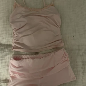 Ljusrosa set - Ljusrosa linne med spetsdetalj längs urringningen och matchande shorts till, perfekt för mysplagg hemma.🩷