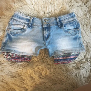 Ljusblå jeansshorts med mönstrade detaljer - Säljer även massa flera shorts!! Midja rakt över: 35,5 +mycket stretch💞 Kan både vika in fickorna och ha de ute💞
