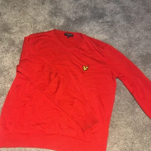Röd tröja från Lyle & Scott - Säljer en röd långärmad tröja från Lyle & Scott med klassisk gul logga på bröstet. Tröjan har rund halsringning och ribbade muddar vid ärmslut och nederkant. Perfekt för dig som gillar stilrena och färgstarka plagg.