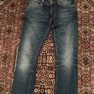 Mörkblå jeansbyxor från Nudie Jeans - Säljer ett par mörkblå jeans från Nudie Jeans med klassisk femficksdesign. Jeansen har en sjukt fin passform. Perfekta för de som utveckla sin stil.