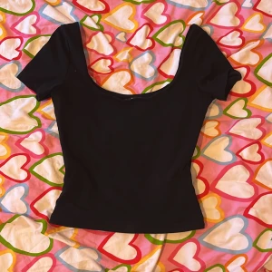 Svart topp med djup urringning från Gina Tricot - Säljer en svart topp från Gina Tricot i storlek XS. Toppen har korta ärmar och en djup, rund urringning. Perfekt att styla med jeans eller kjol för en trendig look.