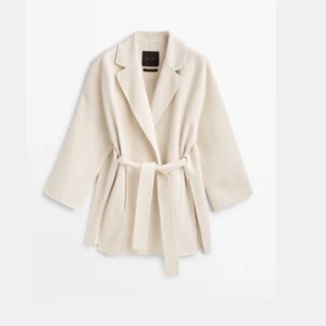 Beige kappa med bälte från Massimo Dutti - Säljer en stilren beige kappa från Massimo Dutti med bälte i midjan och klassisk krage. Jackan har lång ärm och en rak, något oversized passform. Perfekt för höst och vår när du vill vara både snygg och bekväm.