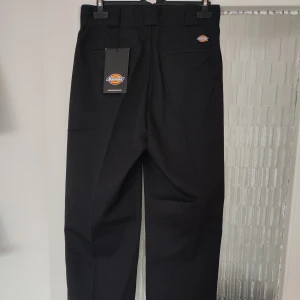 Svarta byxor från Dickies i storlek w26 - Svarta byxor från Dickies i storlek w26. Byxmodellen heter Elizaville Rec. Gjorda av polyester och bomull. Byxorna är helt nya med alla lappar kvar. Nypris på dessa är 749kr.