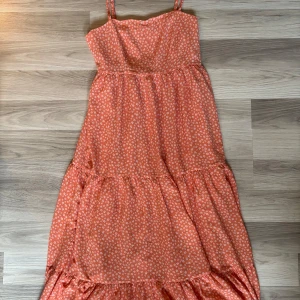 Korallfärgad midsommarklänning från NA-KD - Superfin korallfärgad långklänning från Lisa&Lena x NA-KD! Den har ett blommönster i vitt. Passar perfekt nu till sommaren och midsommar. Endast använd en gång och säljer den då den är för liten.🌼🧡