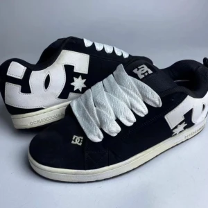 DC skor - Säljer ett par klassiska DC Shoes sneakers i svart med stora vita DC-loggor på sidorna. Skorna har breda vita snören och en platt vit sula. Perfekta för dig som gillar streetwear och skate-stil. Storlek 36 men passar 37! Använda max två gånger.