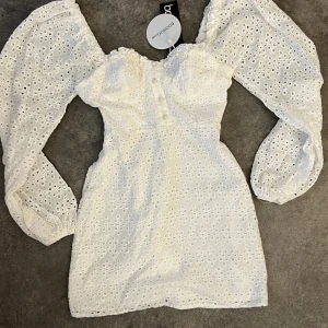Vit broderad klänning med puffärmar från Boohoo🌸💕☀️ - Supersöt vit kortklänning från Boohoo med broderie anglaise-tyg och puffiga långärmar. Klänningen har en söt hjärtformad urringning och markerad midja. Perfekt för sommarens alla tillfällen!
