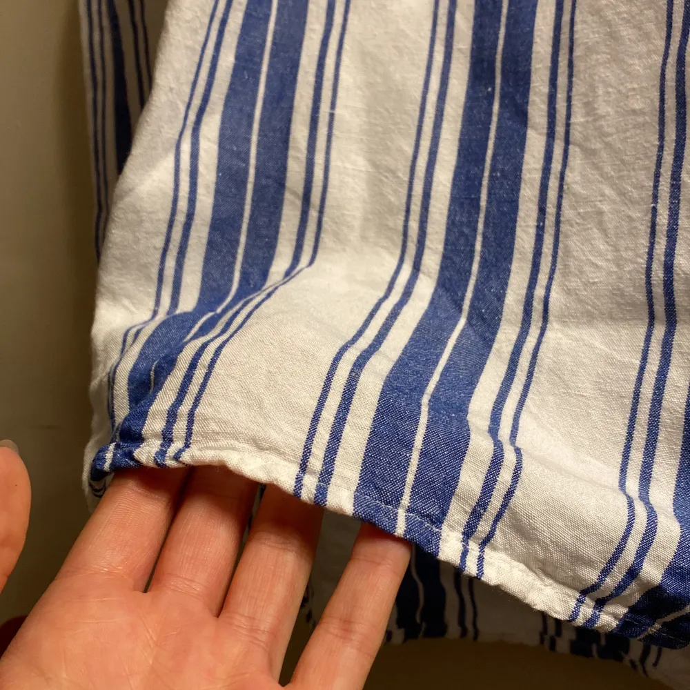 En ärmlös topp från Lindex i vitt och blått. Toppen har en v-ringad hals och är tillverkad i ett mjukt bomullsmaterial, perfekt för sommaren som snart närmar sig💕. Yläosat.