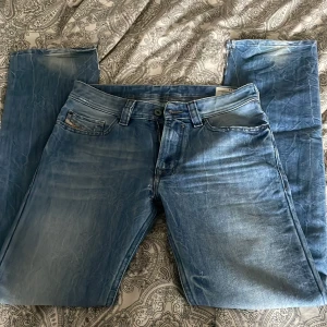 Blå jeans från Diesel Kid - Säljer ett par klassiska blå jeans från Diesel Kid i modell Safari. Jeansen har fem fickor, normal passform och snygga slitningar för en cool look. Perfekta till vardags och lätta att matcha med olika stilar.