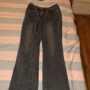 Grå bootcut jeans med broderade bakfickor - Säljer ett par grå bootcut jeans med snygga broderade detaljer på bakfickorna. Jeansen har klassisk femficksdesign och normal passform. Perfekta för dig som gillar en lite vidare siluett nertill.