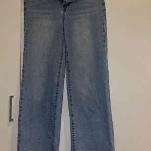 Blå wide leg jeans - Säljer ett par ljusblåa jeans med breda ben och hög midja. Klassisk femficksmodell med knapp och dragkedja framtill. 