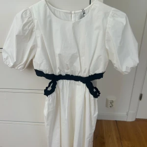 Vit klänning med svarta detaljer från Zara - Superfin vit klänning från Zara med puffärmar och svarta rynkade detaljer i midjan. Den har aldrig använts och har prislappen kvar.