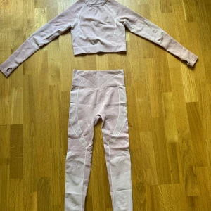 Beige croppad träningströja med matchande tights  - Säljer en beige croppad långärmad träningströja med vita detaljer samt matchande tights. Tröjan har hål för tummarna och ett snyggt urklipp i ryggen. Perfekt för gymmet eller yoga! Materialet är stretchigt och följsamt för maximal komfort.