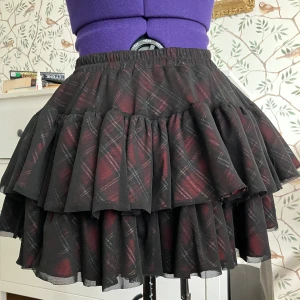 Häftig kjol - Kjol från Queen of Darkness, inte använd. Supercool veckad kjol med flera lager och ett svart meshtyg ovanpå det rutiga tyget. Perfekt för klubben, festivaler, eller en alternativ vardagslook