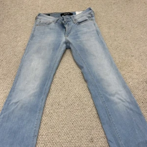 Ljusblå Replay jeans bootcut - Snygga ljusblå jeans från Replay med klassisk femficksdesign och bootcut. Jeansen har diskreta slitningar och ljus tvätt, samt läderpatch bak i midjan. Perfekta för en avslappnad och trendig look.