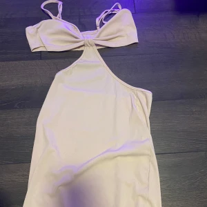 Ljus ribbad långklänning  - Supersöt ljus lång klänning i fin material. Klänningen har smala axelband och en öppen design vid magen. Perfekt för dig som vill sticka ut med en trendig och feminin look.