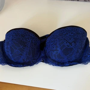 Blå spets bh - Snygg bandeau bh i djupblå spets med svarta detaljer. 