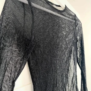 Glittrig meshtopp - Svart långärmad topp i glittrigt mesh-tyg. Från H&M men har klippt av lappen. Storlek: Xs