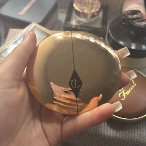 Charlotte Tilbury puder i guldig dosa - Säljer ett pressat puder från Charlotte Tilbury i en lyxig, rund guldig dosa med spegel. Pudret är ljust beige och perfekt för att matta ner huden och ge en jämn finish. Dosan är elegant och smidig att ha med i väskan. Har förpackningen har fått fel färg.