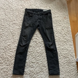 Svarta skinny jeans från Diesel - Svarta jeans från Diesel med klassisk femficksdesign och smal passform. Jeansen har diskret logga på bakfickan och är tillverkade i ett stretchigt denimtyg som sitter tajt längs benen. Perfekta för dig som gillar en clean och stilren look.