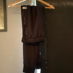 Svarta mjukisbyxor Jack & Jones - Svarta mjukisbyxor från Jack & Jones med elastisk midja och snörning. Byxorna har dragkedjeförsedda fickor och är gjorda i mjukt bomullsmaterial. Perfekta för chill eller träning, med en relaxed och loose passform.