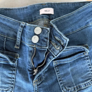 Blå low bootcut jeans - Snygga blå bootcut jeans från Nelly med låg midja. Storlek 36 och passar mig som är 166. Säljs då dom inte kommer till användning.