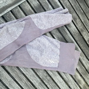Ljuslila ribbade leggings - Snygga ljuslila leggings med ribbade detaljer och en mjuk, stretchig känsla. Perfekta för träning eller chill, med en modern look och bekväm passform. Snyggt mönster i olika lila nyanser som ger extra stilpoäng.