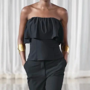 Svart axelbandslös topp med volang - Jättefin tubtopp från Zara som inte kommer till användning. Står att den är i storlek L men passar mer s/m då den är mindre i storleken🫶🏻