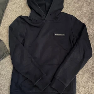 Mörkblå Peak Performance S - Mörkblå hoodie från Peak Performance i storlek S. Klassisk modell med huva, magficka och diskret logga på bröstet. Mjuk och skön bomullsblandning.