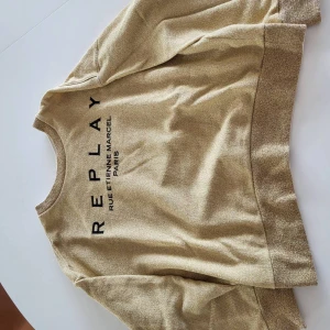 Beige sweatshirt från Replay - Snygg beige sweatshirt från Replay med svart tryck framtill. Tröjan har rund halsringning, breda muddar vid ärmslut och nederkant samt en relaxed passform. Perfekt för dig som gillar en enkel men stilren look.