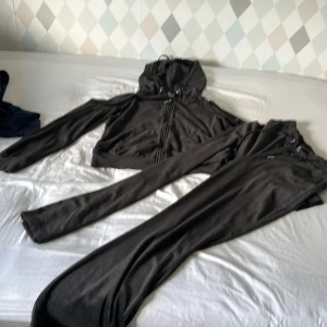 Svart croppad hoodie med dragkedja - Säljer en svart croppad hoodie med dragkedja och huva. Tröjan har långa ärmar och är i ett mjukt material, perfekt för en chill och avslappnad stil. Passar dig som gillar streetwear och vill ha något bekvämt men ändå snyggt. Tröjan är i storlek M och byxorna S