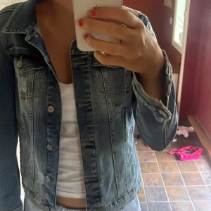 Blå jeansjacka med broderade blommor - Snygg blå jeansjacka med broderade blommor på ena axeln och ärmen. Jackan är i storlek XS🩷