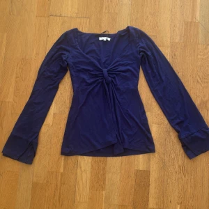 Mörkblå långärmad topp Design by Si - Supersnygg mörkblå långärmad topp från Design by Si. Toppen har en djup v-ringning och en cool knytdetalj framtill som ger en unik look. Tillverkad i mjuk bomull, perfekt för dig som gillar stilrena och trendiga plagg. Kontakt vid frågor😇