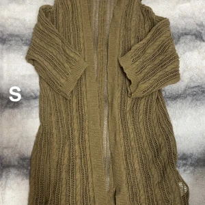 Beige stickad kofta med kort ärm - Säljer en beige stickad kofta med korta ärmar och öppen front. Koftan har ett snyggt kabelstickat mönster och är perfekt att slänga över en topp för en chill look. Passar dig som gillar lager på lager och vill ha något mysigt men luftigt.🌸Kofta utan knappar. Fint använt skick. Storlek S 