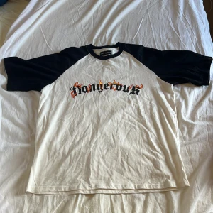 Oversized t-shirt med svarta ärmar - Snygg oversized t-shirt från Dangerous DNGRS med svart-vita kontraster och coolt flames-tryck på bröstet. Klassisk raglanmodell med svarta korta ärmar och vit kropp. Perfekt för dig som gillar streetwear och vill sticka ut lite extra.