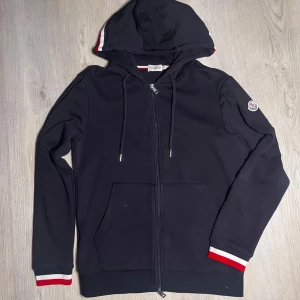 Mörkblå zip från Moncler  - Mörkblå zip kofta från moncler väldigt skön och lätt att bära, man blir inte för varm eller för kall i den. 