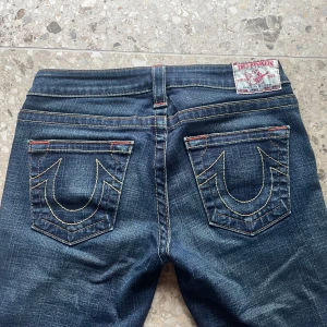 True Religion jeans  - Säljer ett par blå jeans från True Religion med jätte fina sömmar och jättefina bakfickor. Midjemått: 35,5 cm rakt över, Innerbenslängd: 80cm, Grenmått: 17cm🫶