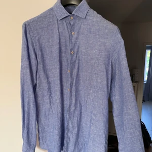 Blå linneskjorta från Park Lane S - Snygg blå skjorta från Park Lane i 100% linne. Skjortan har klassisk krage, knäppning framtill och långa ärmar. Perfekt för en avslappnad men stilren look under varmare dagar.