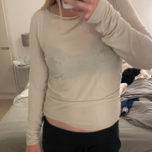 Beige långärmad topp  - En enkel och stilren beige långärmad topp. Modellen är figurnära med rund halsringning och långa ärmar, perfekt att matcha med jeans eller kjol för en clean look.